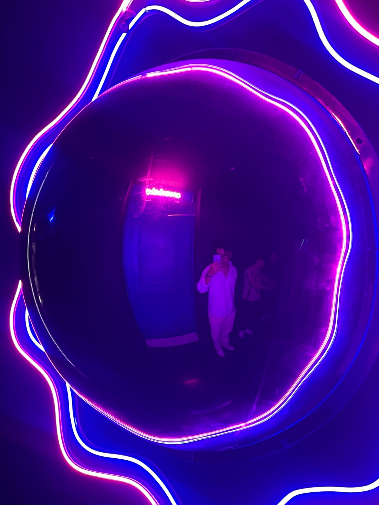 Sencillos Fotografía con luces neón moradas y azules, reflejados en una superficie circular, usada como arte visual.