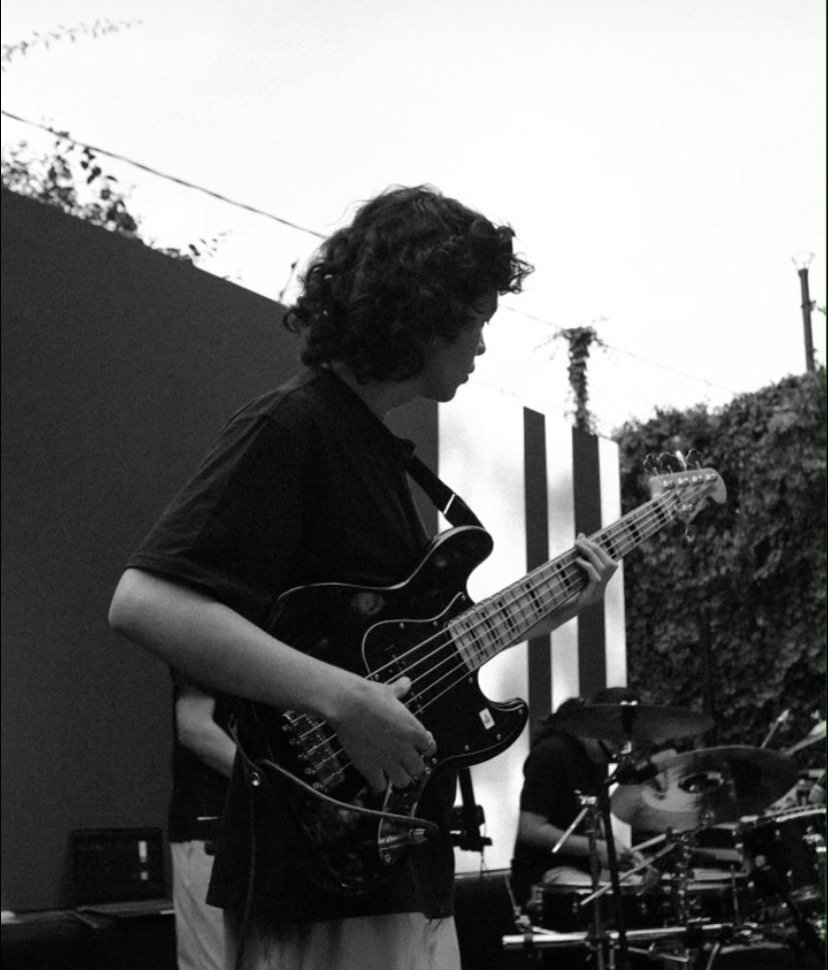 Top escuchados Hombre tocando un instrumento de cuerdas al aire libre con más instrumentos de fondo. la imagen fue capturada a blanco y negro.